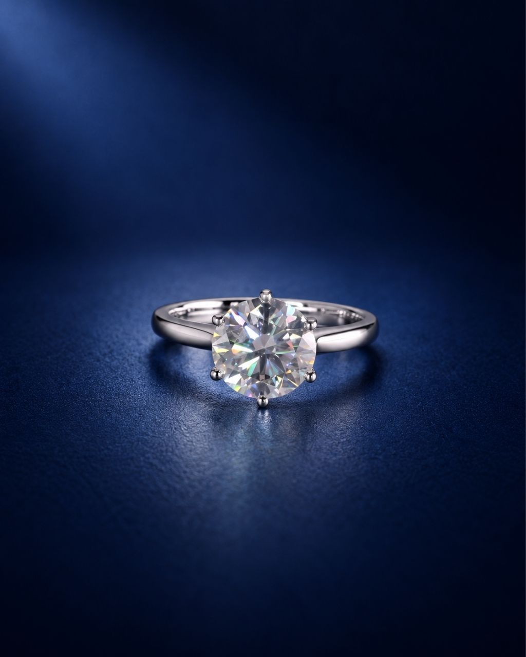 6-prong round moissanite solitaire engagement ring in polished 14K solid white gold, featuring a brilliant round-cut stone on a deep navy blue background