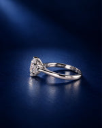 Side view of a 6-prong round moissanite solitaire engagement ring in polished 14K solid white gold, showcasing the raised basket setting and slender band on a deep navy blue background.