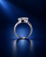 Side profile of a pear-cut moissanite engagement ring in polished white gold, highlighting the elevated stone setting and sleek band against a deep navy blue background.